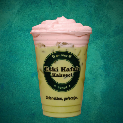 Şeffaf bardakta katmanlı yeşil matcha ve pembe çilek püresi karışımı soğuk içecek.