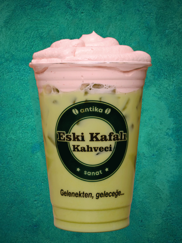 Şeffaf bardakta katmanlı yeşil matcha ve pembe çilek püresi karışımı soğuk içecek.